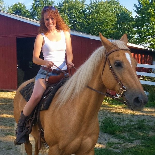 Original photo: a woman riding her palomino by a red barn.